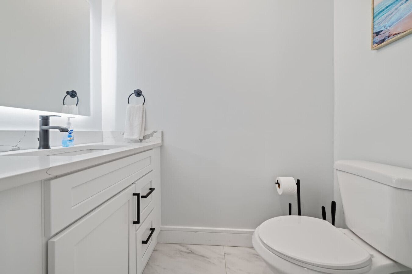 Ein modernes Badezimmer mit einem weißen Waschbecken, einer Toilette und einem Handtuchhalter.