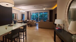 A modern living room with a dining area, large windows, and a ceiling fan.