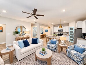 A modern living room with a sofa, armchairs, a coffee table, and a dining area with chairs and a table.