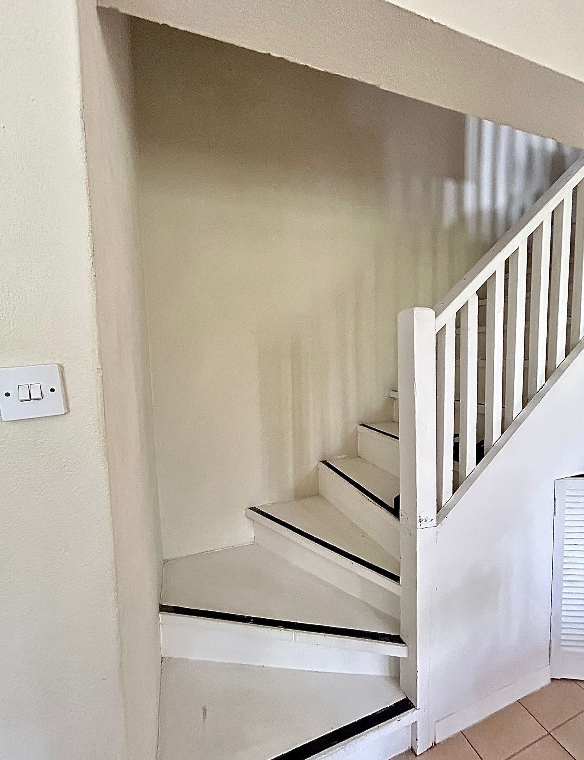Una escalera blanca con detalles negros que lleva a un rellano.