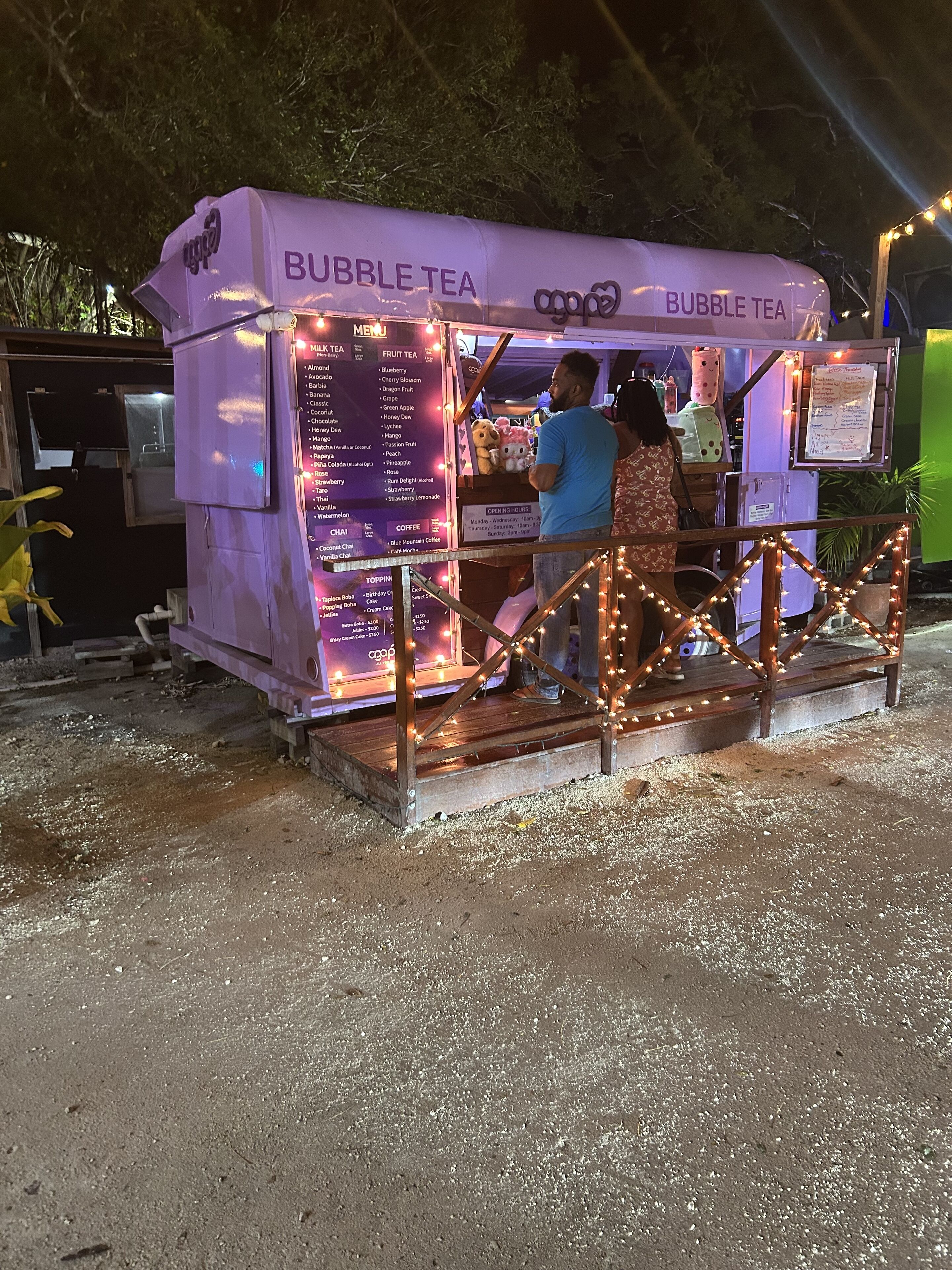 Ein Bubble-Tea-Stand mit einer Speisekarte, die verschiedene Teesorten anbietet, und einer kleinen Bühne für Auftritte.