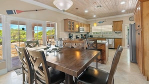A spacious kitchen with wooden cabinets, a dining area with a large table and chairs, and a view through the glass doors. - NEW 3 BDR villa near Jolly Hall beach and Turtle beach in Welcoming George Town (George Town)