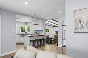 Une cuisine moderne avec des meubles blancs, un îlot central en bois et un coin repas comprenant une table et des chaises.