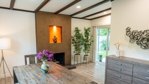 A modern kitchen with wooden cabinets, a dining table with a vase of flowers, and a fireplace. - UPSCALE & UPGRADED 3BR HOUSE in ENCINO with GARAGE & LARGE FENCED YARD/PATIO p84 (Los Angeles)