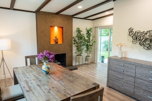 Une cuisine moderne avec des meubles en bois, une table à manger agrémentée d’un vase de fleurs et une cheminée.