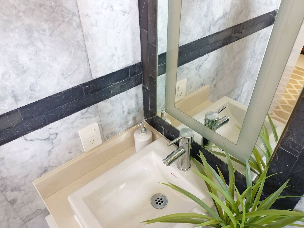 A bathroom with a marble sink, a mirror, and a black-framed mirror.
