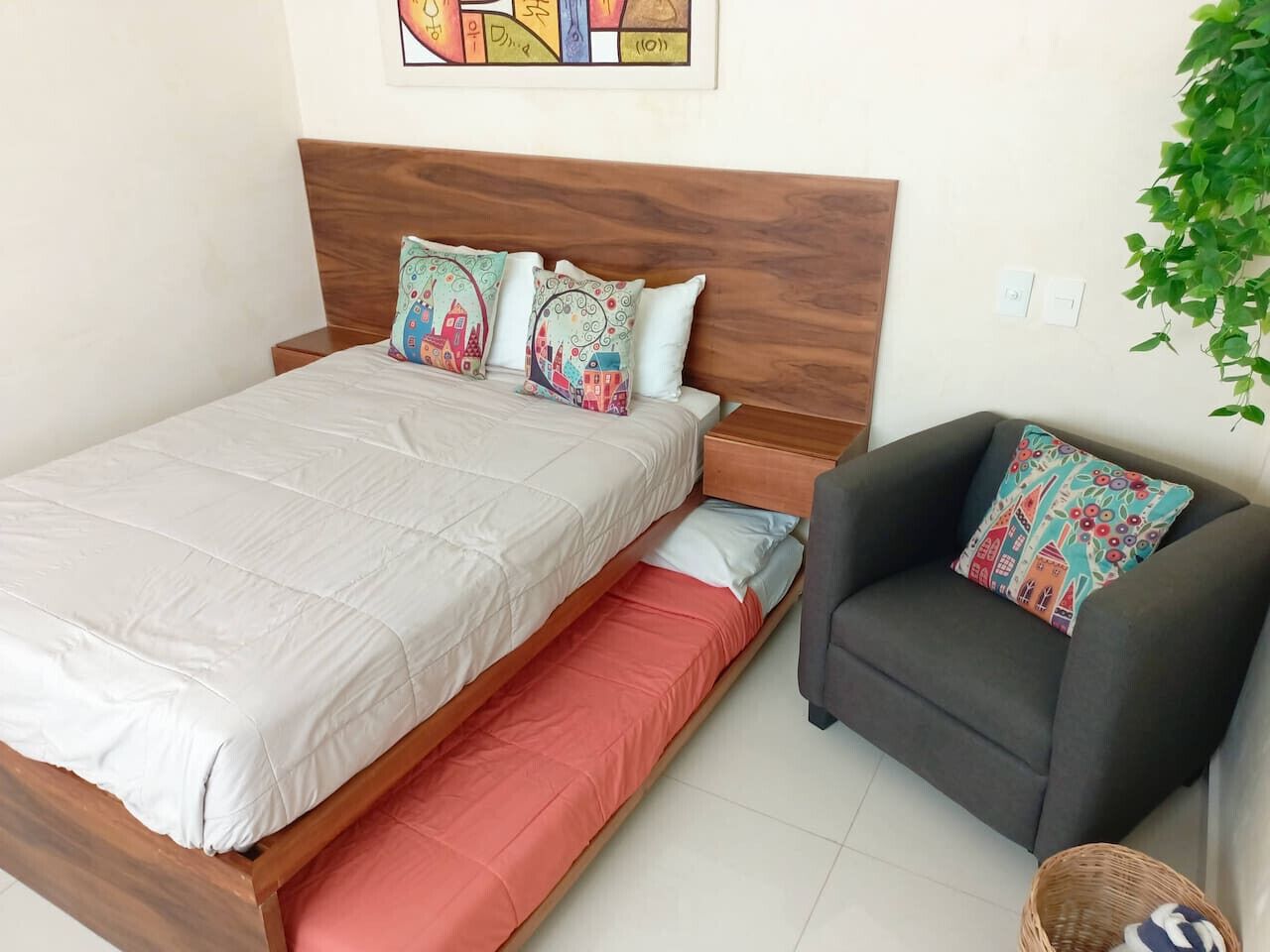 Un dormitorio con una cama, una silla e interruptor de luz en la pared.