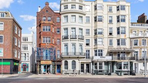 En rad av fler våningar höga byggnader med en blandning av olika arkitektoniska stilar, inklusive en hörnbildning med en balkong och en byggnad med en skylt som visar texten "WERKS".