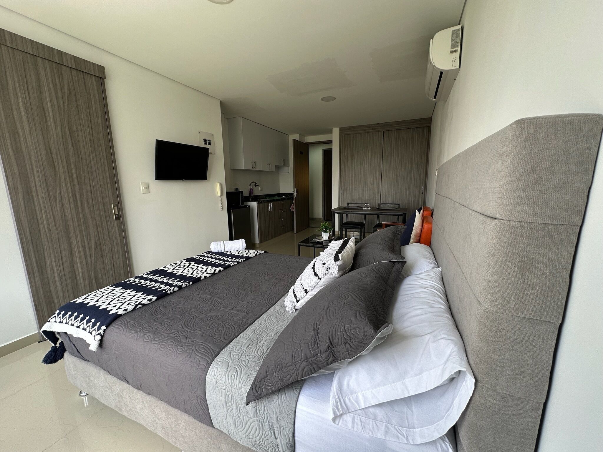 Una habitación de hotel moderna con una cama grande, un televisor de pantalla plana, una kitchenette y un comedor.