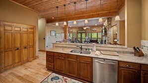 A spacious kitchen with wooden cabinets, a large island with a sink, and pendant lighting. - Mountain Home with Mountain Views (Sugar Mountain)