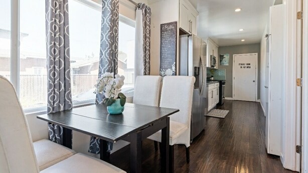 A modern kitchen with white cabinets, a refrigerator, and a dining area with a table and chairs.