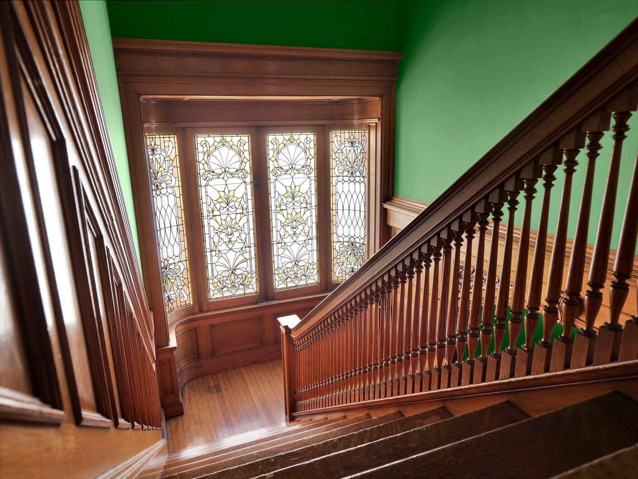 A staircase with wooden balusters and a green wall.