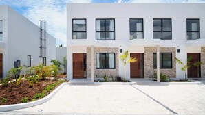 Un edificio moderno a più piani con tetto piatto, ampie finestre e un giardino curato con diverse piante.
