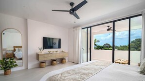 Una camera da letto con un letto, una televisione, un comò in legno e un balcone con vista.