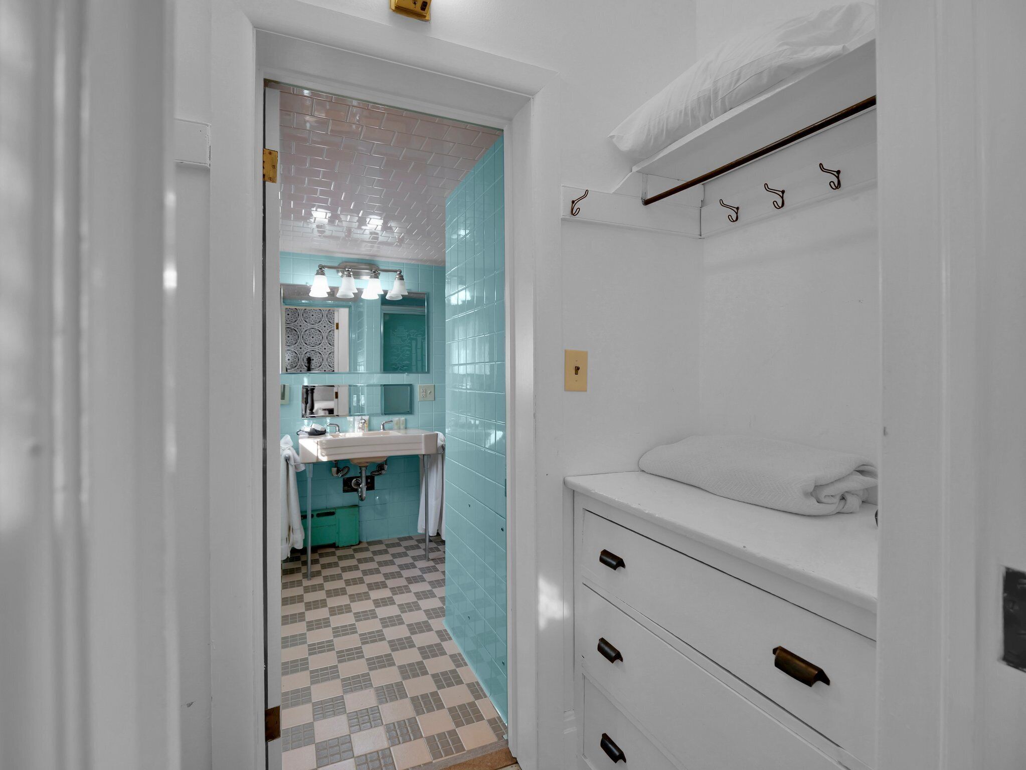 A bathroom with a checkered floor, a sink, a mirror, and a towel rack.