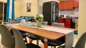 A compact living space with a dining area, kitchen, and a sofa with blue cushions. - POSADA DEL CARIBE (Santo Domingo Este)