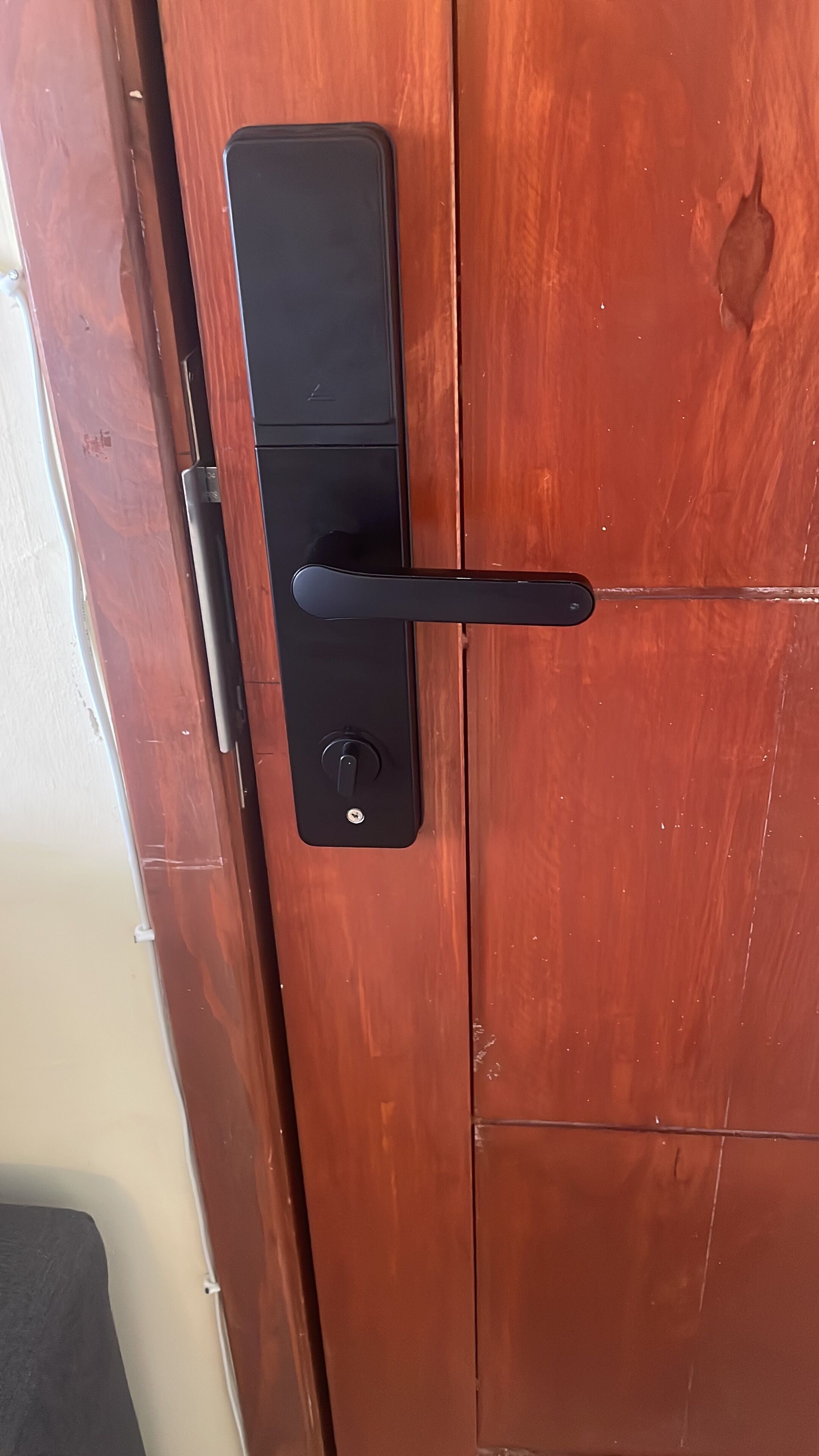 A wooden door with a black handle and a keyhole.