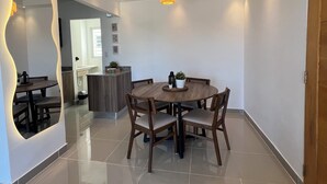 Un espace de salle à manger moderne avec une table ronde, des chaises en bois et un luminaire suspendu.