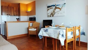 A compact living space with a kitchenette, dining area, and a painting of a bridge.