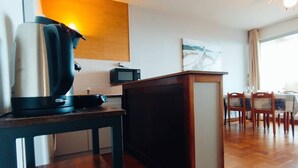 A compact living space with a kitchenette, a dining area, and a large window.