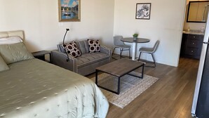 Une pièce moderne et bien éclairée, comprenant un lit, un canapé, une table basse et une petite table à manger.