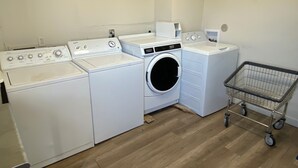 Une buanderie équipée d’un lave-linge, d’un sèche-linge et d’un chariot en métal.