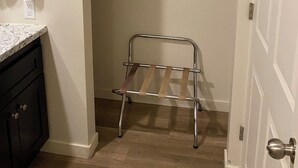 Un dressing avec un étendoir métallique, une tringle à vêtements et une étagère où sont pliées des serviettes.