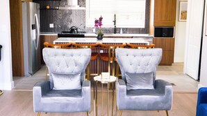 Een moderne keuken met een centraal eiland, twee barkrukken en een zithoek met twee stoelen.
