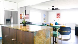 A modern kitchen with a marble island, built-in appliances, and a dining area with a sofa and chairs.