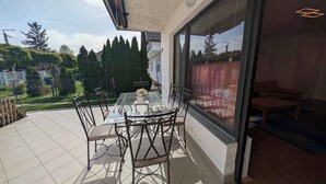 A glass-top dining table with chairs on a balcony with a view of trees and houses. - Holiday apartment with terrace, air conditioning and WLAN (Siófok)