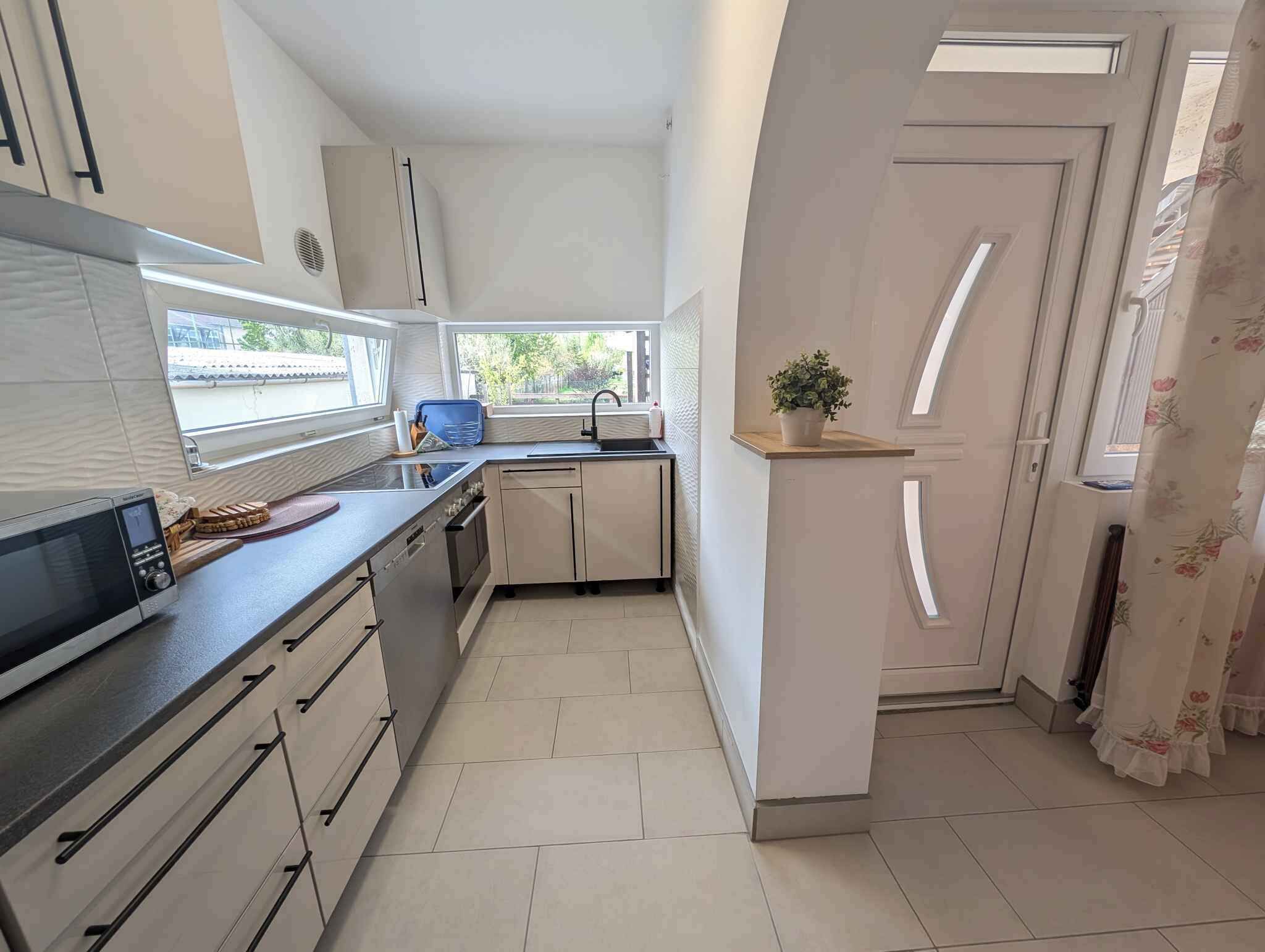 A compact kitchen with a microwave, sink, and cabinets.