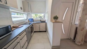 A compact kitchen with a microwave, sink, and cabinets. - Holiday apartment with terrace, air conditioning and WLAN (Siófok)