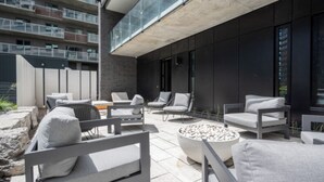 A modern outdoor seating area with multiple lounge chairs and a fire pit. - Mid-century getaway (Brossard)