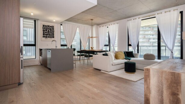 A modern living room with a sofa, a dining table, and a kitchen area. - Mid-century getaway (Brossard)