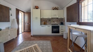 A modern kitchen with white cabinets, a built-in oven, and a dining area with a wooden table and chairs.