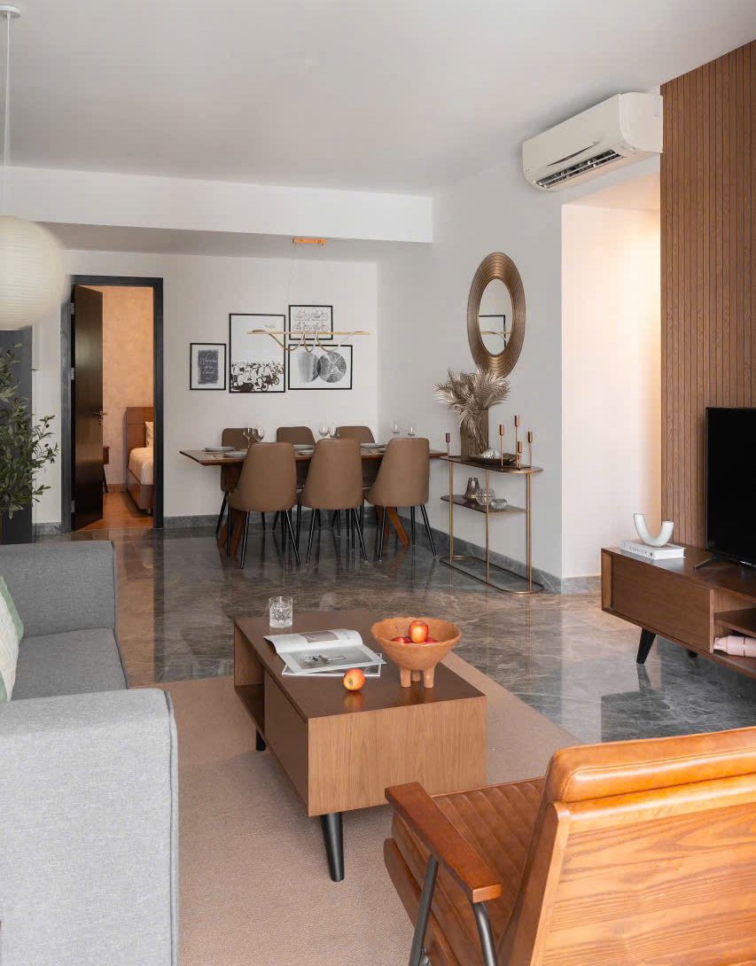 Un salon moderne comprenant un canapé, une table basse, un meuble pour la télévision et un coin repas.
