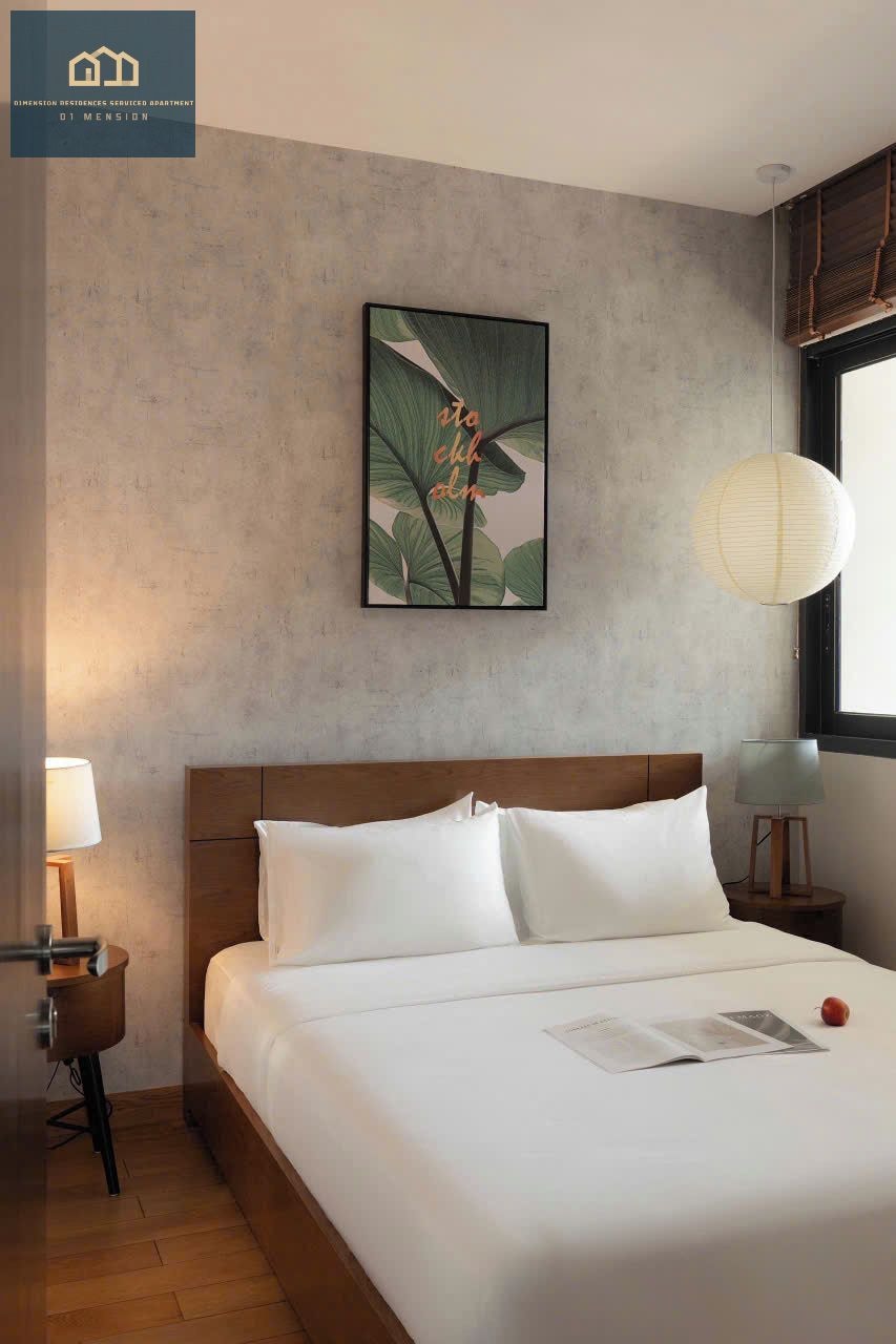 Une chambre d’hôtel avec un lit, une table de chevet, une lampe, un tableau accroché au mur et une fenêtre avec des stores.
