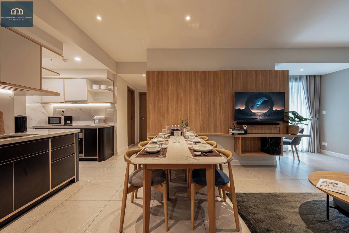 Una sala de estar moderna con comedor, cocina y televisor montado en la pared.