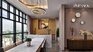 A modern hotel room with a large window, a marble dining table, and a view of the cityscape.