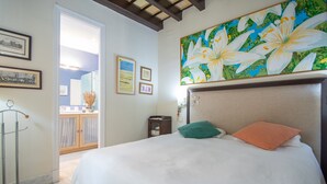 Ein Hotelzimmer mit einem großen Bett, einem Blumenbild an der Wand und Blick auf den Balkon.