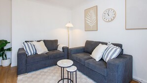 A modern living room with two grey sofas, a small round table, and a floor lamp. - Little Fig Retreat - 5 mins to Fremantle (Samson)