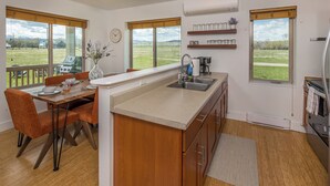 Una cocina moderna con una isla grande, armarios de madera y vista a un campo verde.