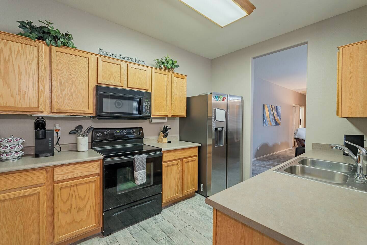 A modern kitchen with wooden cabinets, a black stove, a microwave, a refrigerator, and a sink.