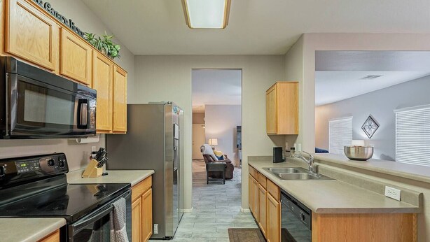 A modern kitchen with wooden cabinets, stainless steel appliances, and a central island with a sink.