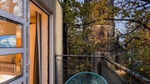 Ein Balkon mit blauem Stuhl, einem Fenster und Blick auf ein historisches Gebäude.