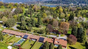 An aerial view of a residential area with houses, a swimming pool, and a lake in the background. - Country House Montorfano (Capiago Intimiano)