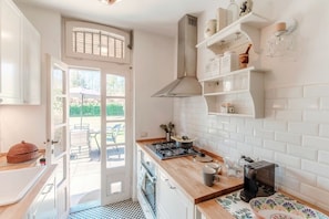 Una cocina con armarios blancos, estufa y cafetera.