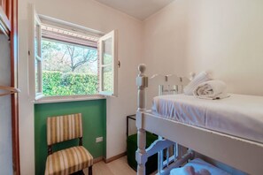 Una habitación con una cama doble, una silla, un ventanal con vistas a la vegetación y una mesita con toallas.
