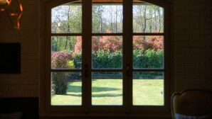 A room with a large arched window, a wooden chair, and a hanging light fixture. - Country House Montorfano (Capiago Intimiano)