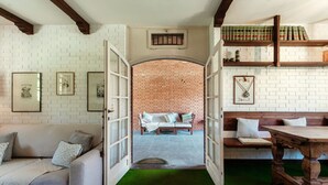 A room with a white brick wall, a green carpet, a wooden bench, a sofa, and a table. - Country House Montorfano (Capiago Intimiano)